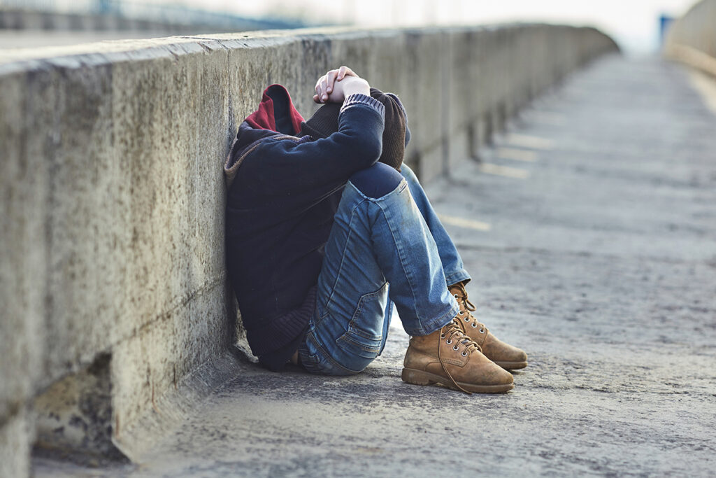 young homeless boy sleeping on the bridge, poverty, city, street.