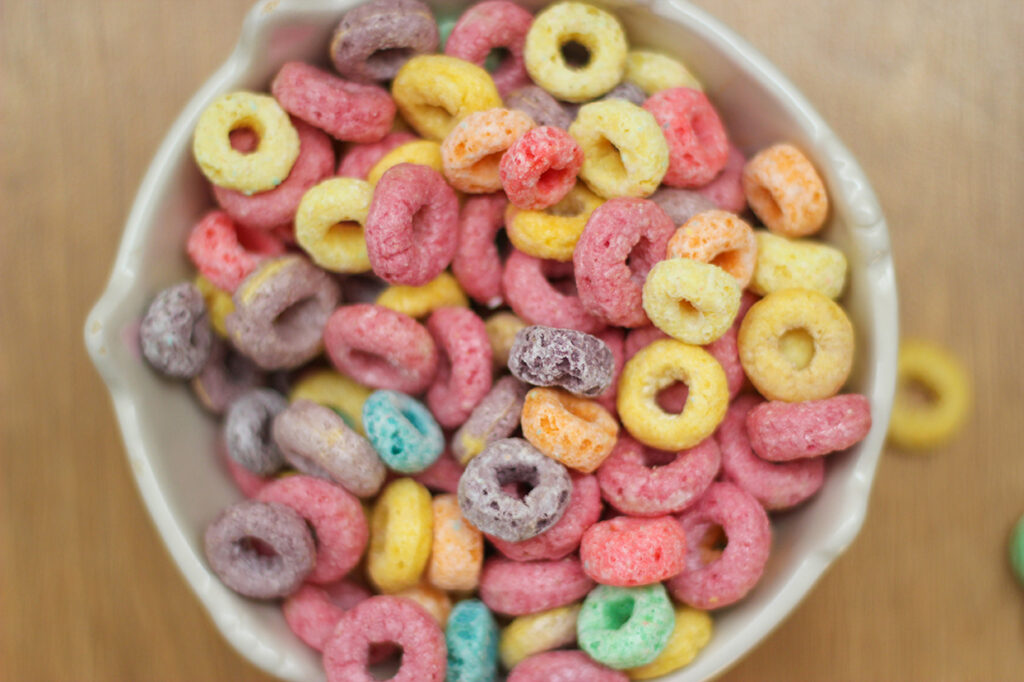 multicolored cereals in a white bowl on wood background